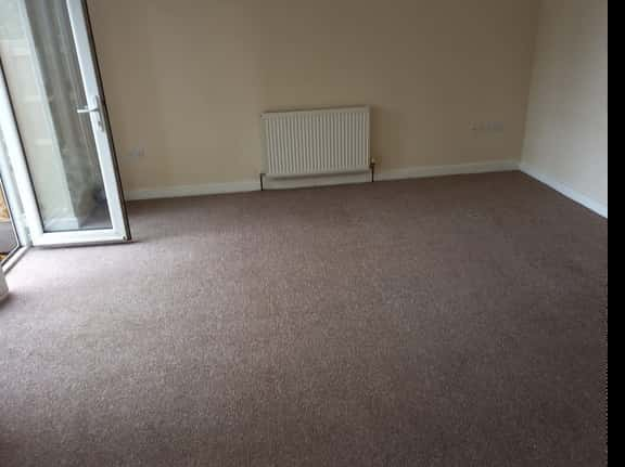 This is a photo of a living room that has been cleaned by K&S Carpet Cleaning, it is a brown carpet, and has been cleaned to a very high standard.